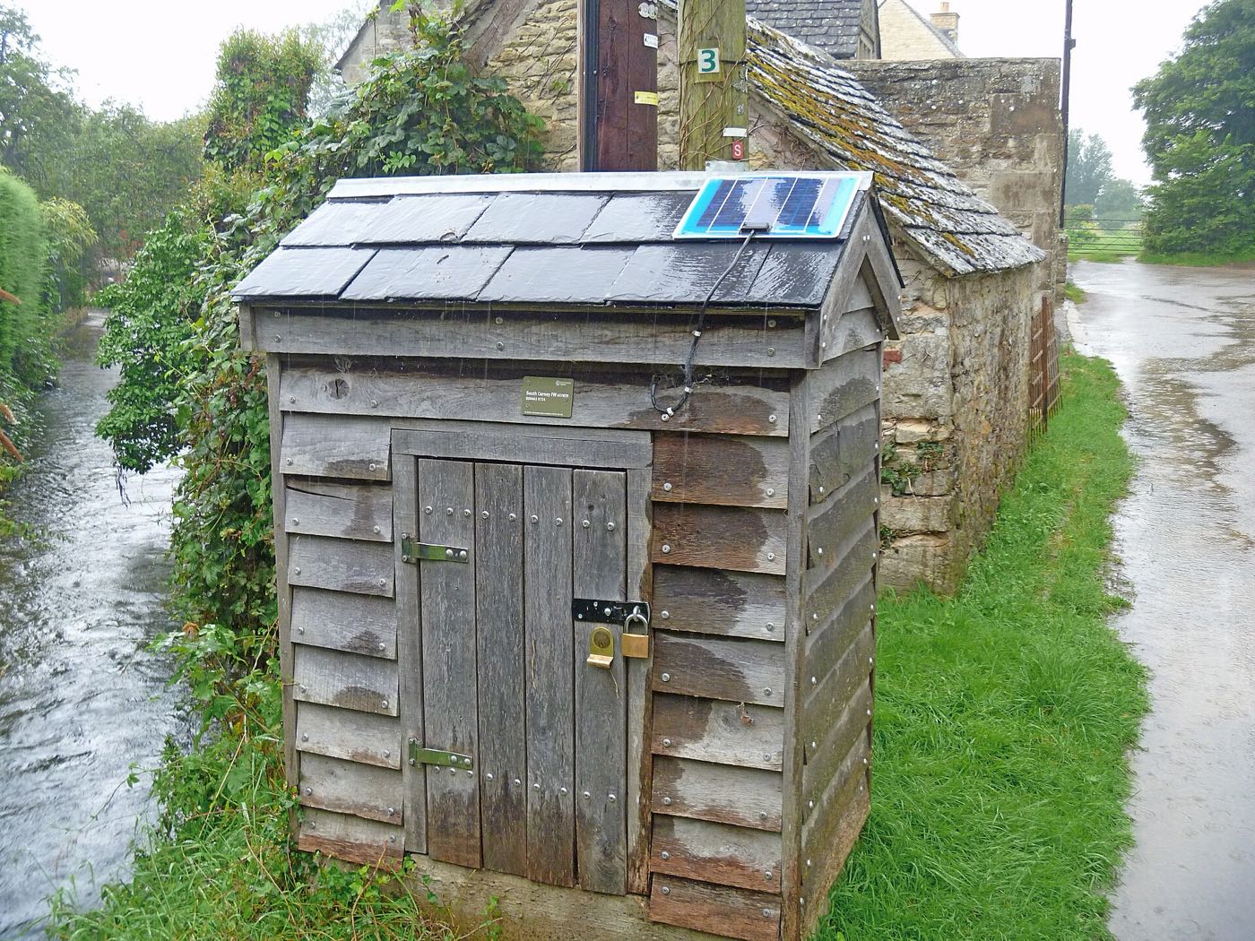 A solar-powered river-level gauging station beside a rising brook in heavy rain